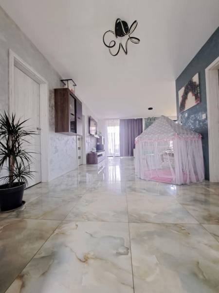 A hallway in a family house with shiny tiles and a children's tent.