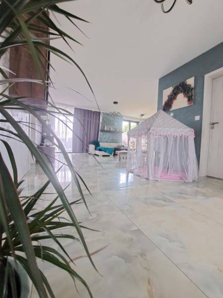 Interior of a family house with a tent for children on a shiny floor and plants.