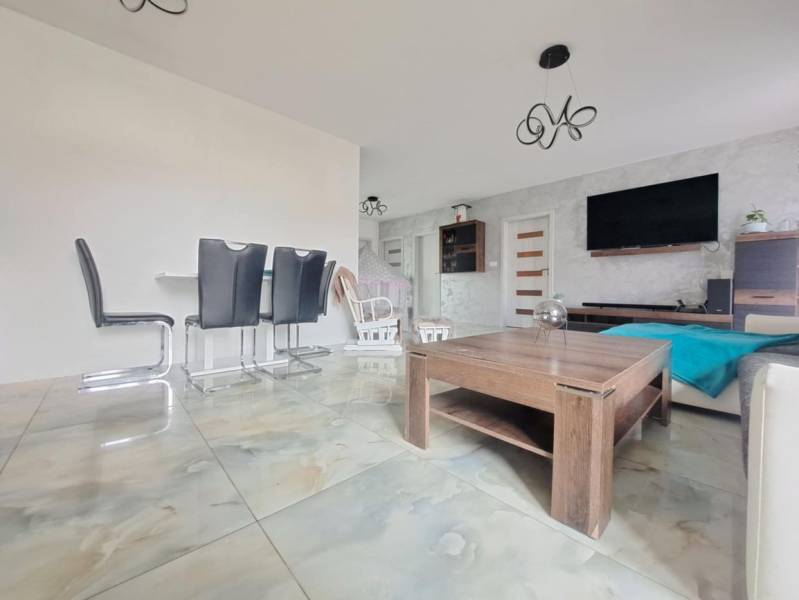 Interior of a family house with light tiles, modern furniture, and a wall with a television.