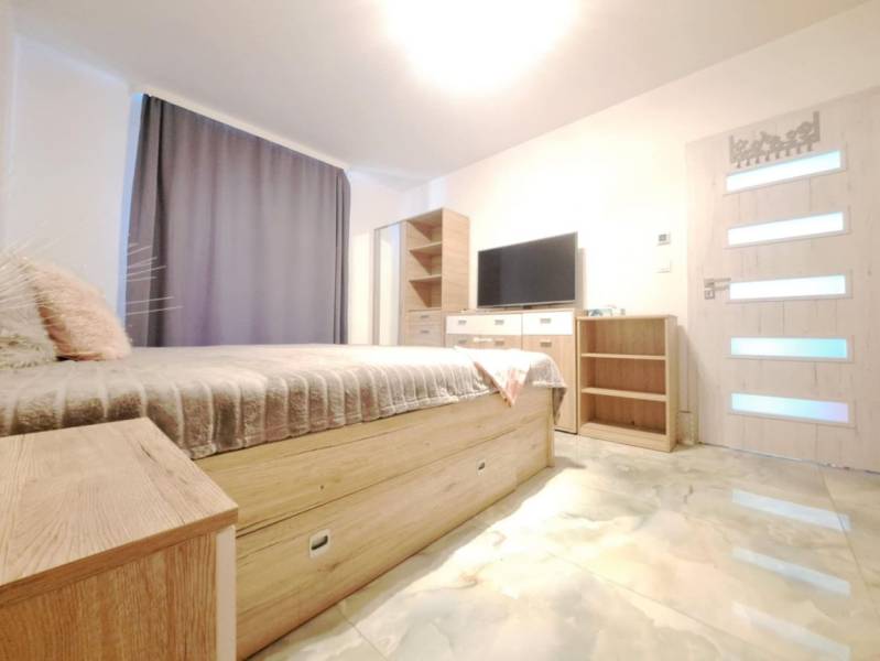 Bedroom in a family house with a bed, wardrobe, television, and floor with a wooden decor.
