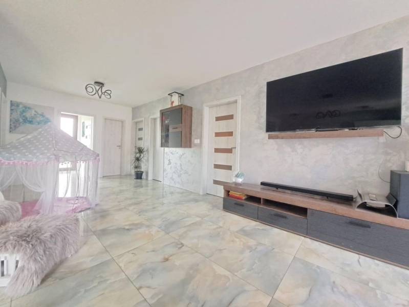 Living room in a family house with a TV on the wall, a tent, and ceramic flooring.