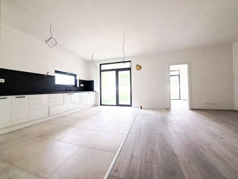 Spacious kitchen in a family house with a wooden decor floor and large windows.