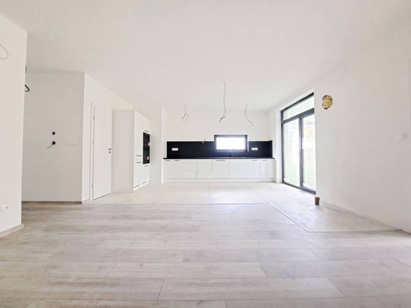 Spacious kitchen with black tiles and a wooden decor floor in a family house.