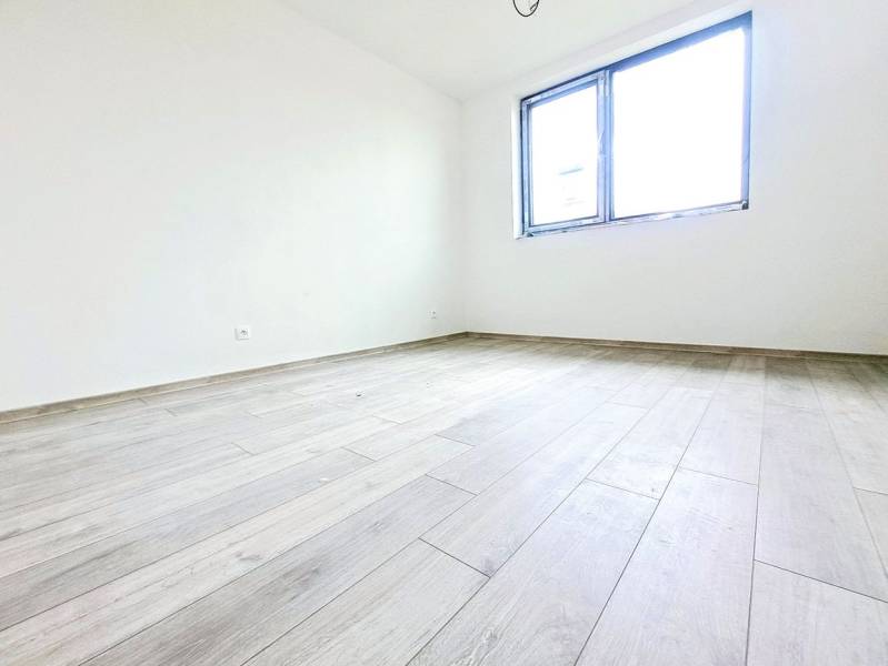 An empty room with a wooden floor and a large window in a family house.