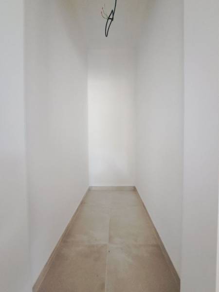 A narrow hallway in a family house with white walls and a light floor.