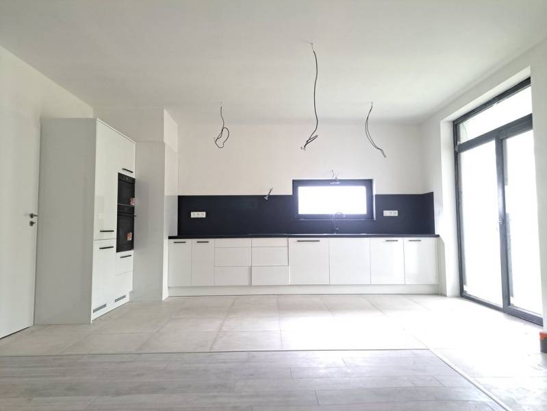 A kitchen in a family house with a wooden decor floor, white cabinets, and built-in appliances.