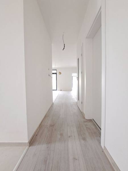 A hallway in a family house with a wooden decor floor and white walls.