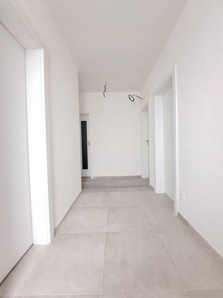 A bright hallway in a family house with white walls and light tiles.