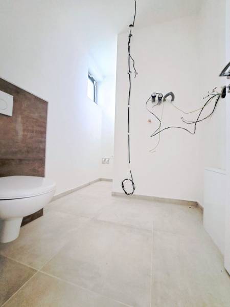 Bathroom in a family house with loose cables and a toilet, without accessories.