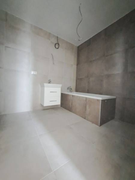 A bathroom in a family house with tiles and a bathtub on neutral flooring.