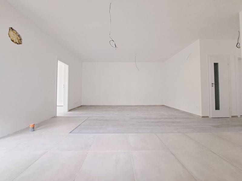 A spacious room with a wooden-decor floor and white walls in a family house.
