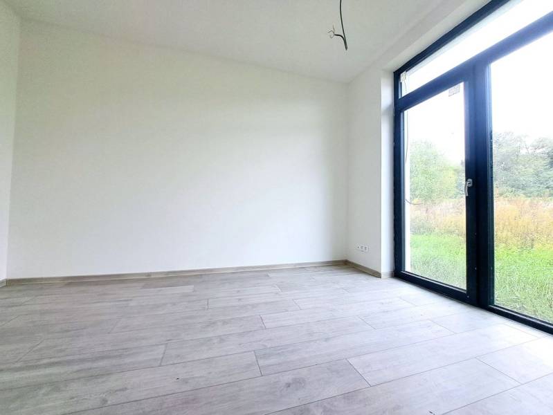 An empty room with a large window and a wooden decor floor in a family house.