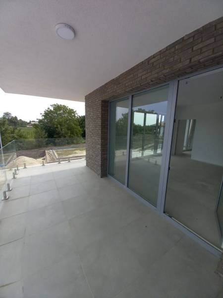 Balcony of a 2-room apartment in Galanta with tiles and glazing, surrounded by greenery.