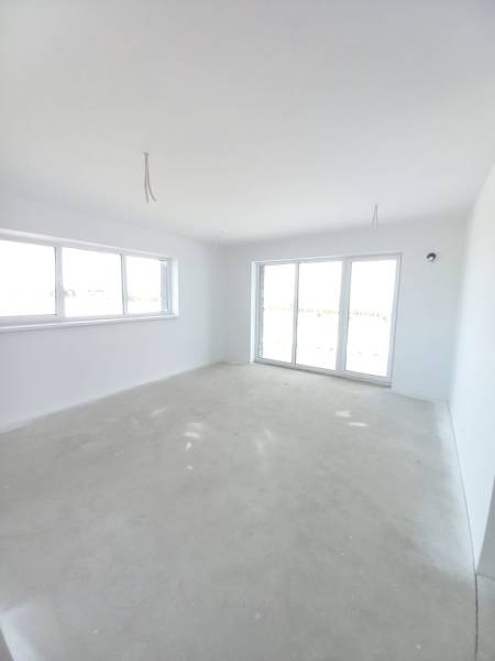 A spacious room in a 2-room apartment with light walls and large windows.