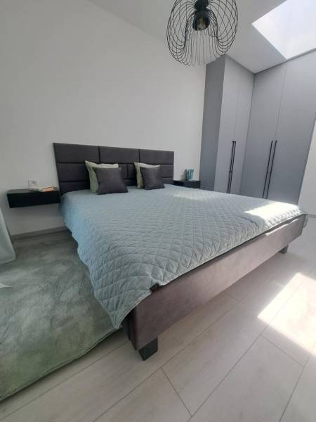 Bedroom with a large bed, gray wardrobes, and a black chandelier in a 2-room apartment.