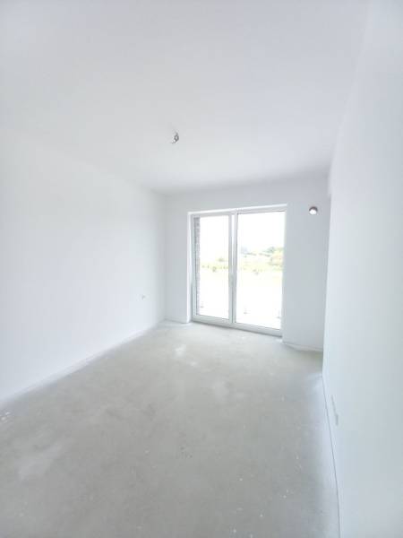 A bright room in a 2-room apartment with a large window and white walls.