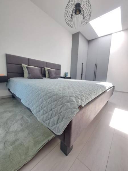 Bedroom in a 2-room apartment with light from a skylight and minimalist furnishings.