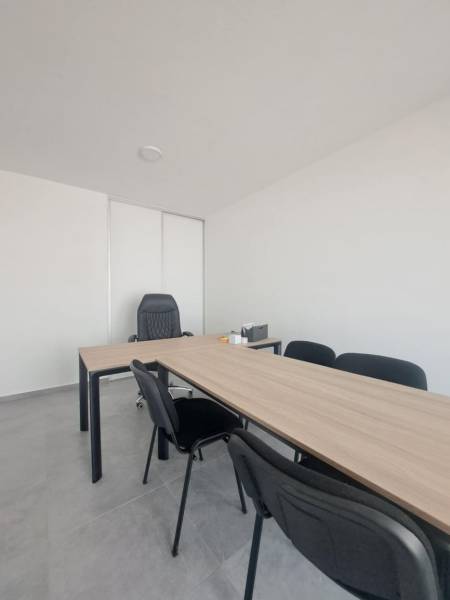 Office desks and black chairs in commercial spaces with a minimalist interior.