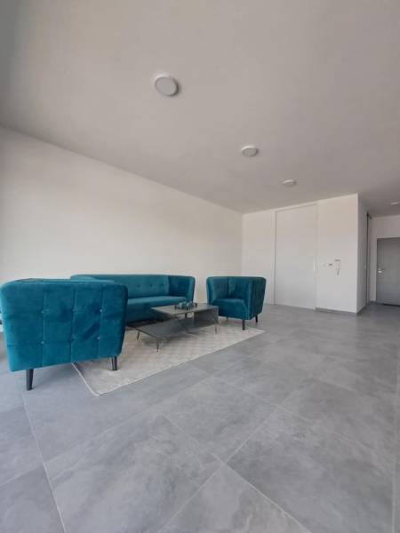 Commercial space with blue sofas, a coffee table on a carpet, and gray tiles.