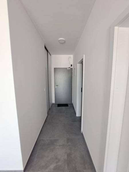 A corridor in commercial premises with white walls and tiles in neutral tones.
