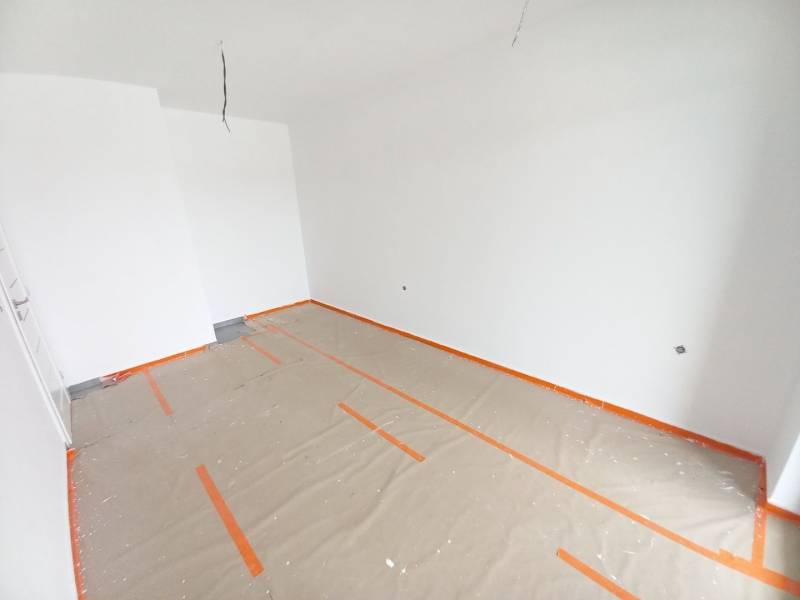 Unfinished commercial space with white walls and a floor covered with protective paper.
