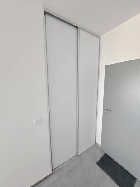 White sliding wardrobe in commercial premises with simple grey doors.