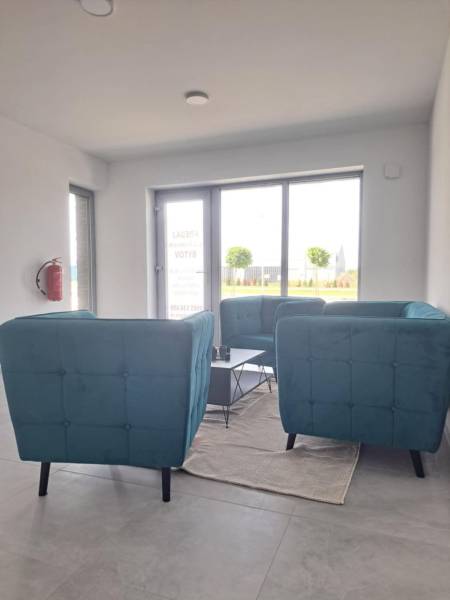 Blue chairs, coffee table, white walls, light flooring, interior of commercial premises.