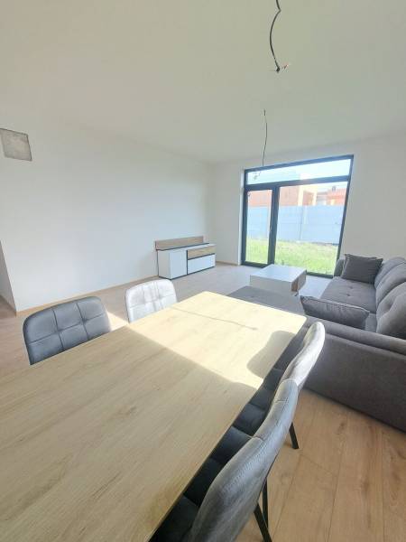 Dining room in a family house with a sofa and wood-patterned flooring.
