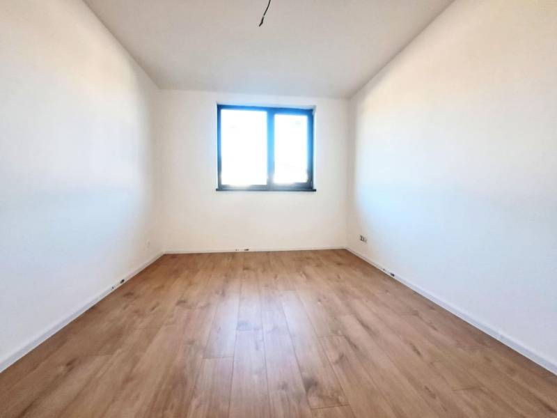 A view of a room with white walls and a wood-patterned floor in a family house.