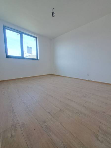A room in a family house with a wooden decor floor and a large window.