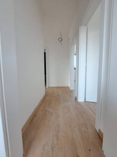 A hallway with white walls and a wooden-decor floor in a family house.