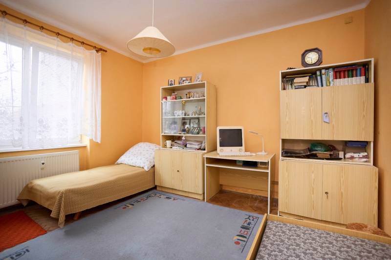 A room in a 3-room apartment with a bed, wardrobes, an old computer, and a lit lamp.
