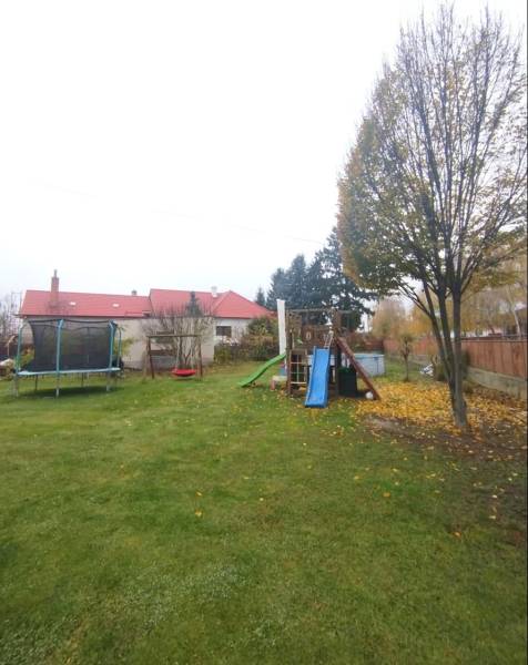 A family house in Dunajská Streda with a grassy garden, a trampoline, and a children's playground.