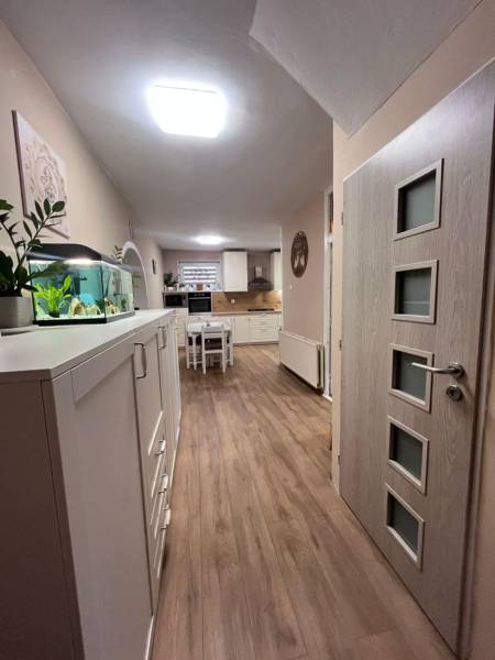 Interior of a family house with a kitchen, white furniture, and a wooden decor floor.