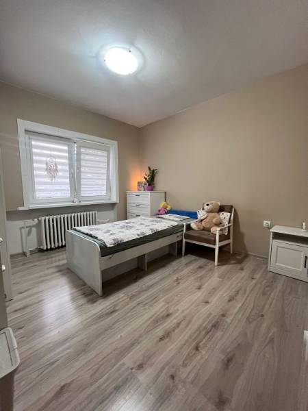 Children's room in a family house with a bed, chair, and floor with wooden decor.