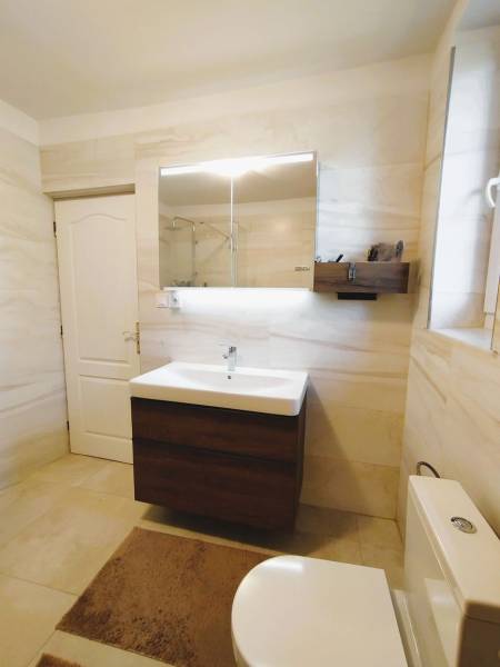 A bathroom in a family house with white walls and a sink with a mirror.