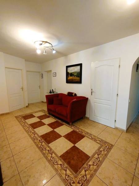 A hallway in a family house with a red armchair and tiles.