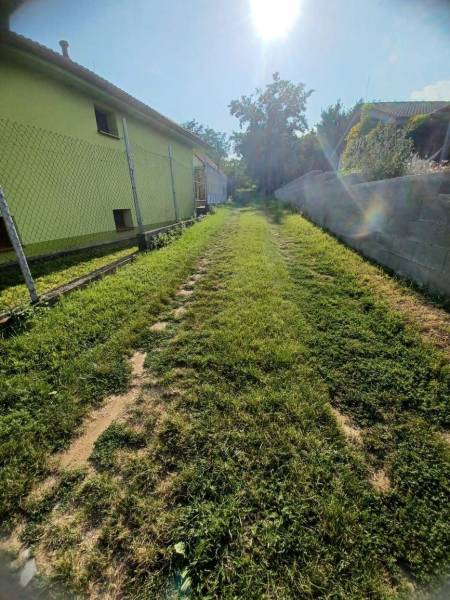 Plots - housing in Veľké Zálužie with a grassy path between the fence and the wall.