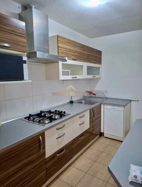A kitchen in a 4-room apartment with a gas stove, extractor hood, and a wooden decor kitchen unit.