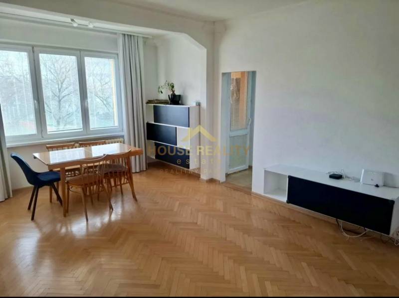 Dining room with a wooden table and chairs, floor with wooden decor in a 4-room apartment.