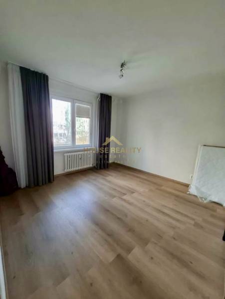 Empty room with wood-patterned flooring and a large window, 4-room apartment.