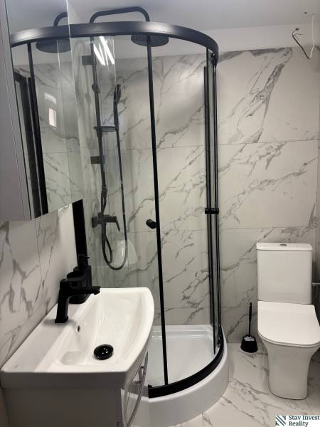 Bathroom of a family house with marble tiles, a shower corner, and a sink.