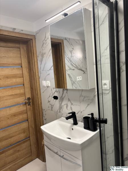 Bathroom with wooden door, sink, and mirror in a family house.