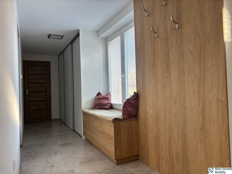 A hallway in a family house with coat hooks and seating with a cushion, floor with wood decor.