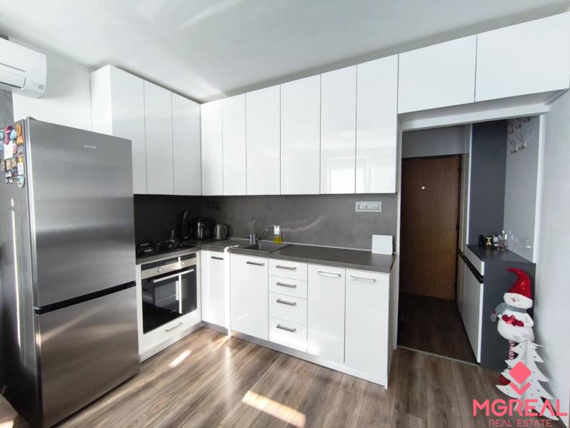 A kitchen with white cabinets and a wood-patterned floor in a studio apartment.