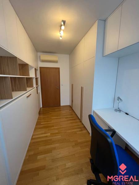 A study with white furniture, built-in wardrobes, and a wooden decor floor in a 3-room apartment.