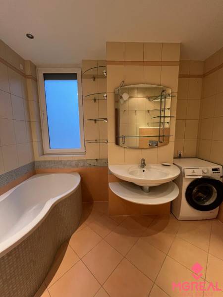 A bathroom in a 3-room apartment with a bathtub, sink, washing machine, and tiles.