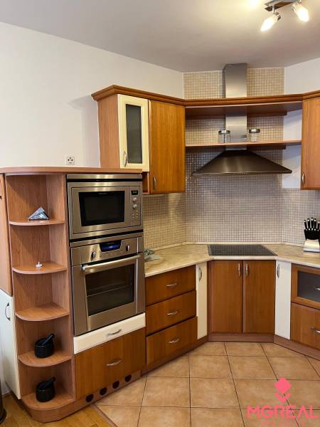 A kitchen in a 3-room apartment with a wooden decor floor and a corner countertop.