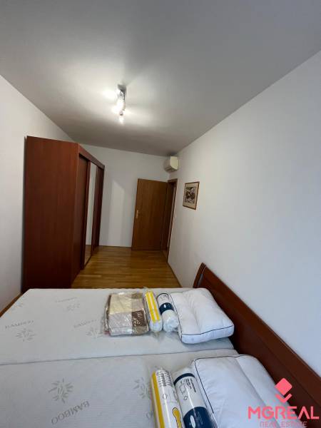 Bedroom with a built-in wardrobe and bed, wooden decor flooring in a 3-room apartment.