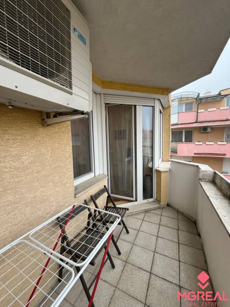 A balcony with furniture and a washing machine in a 3-room apartment.
